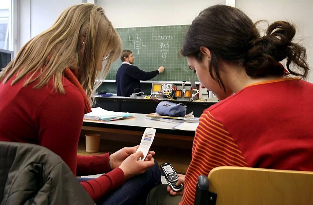 Беспалевно сидеть в телефоне на уроке. Мобильник в школе. школьник с телефоном на уроке. гаджеты в школе. педагог с телефоном.