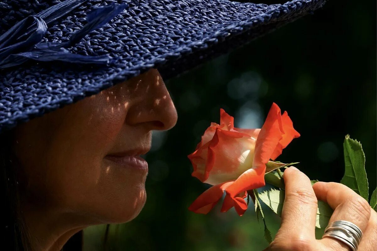Чувствую запах цветов. Женщина в шляпе с розой. Занюхнул в шляпе. Нюхает шляпу. Женщина нюхает цветы фото.