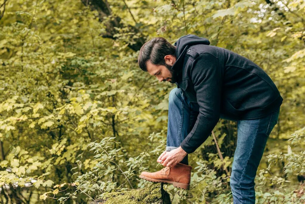 Мужчина завязывает шнурки. Девушка завязывает шнурки мужчине. Связывание человека. Завязывать людей. Парень завязывает шнурки на желтом фоне.