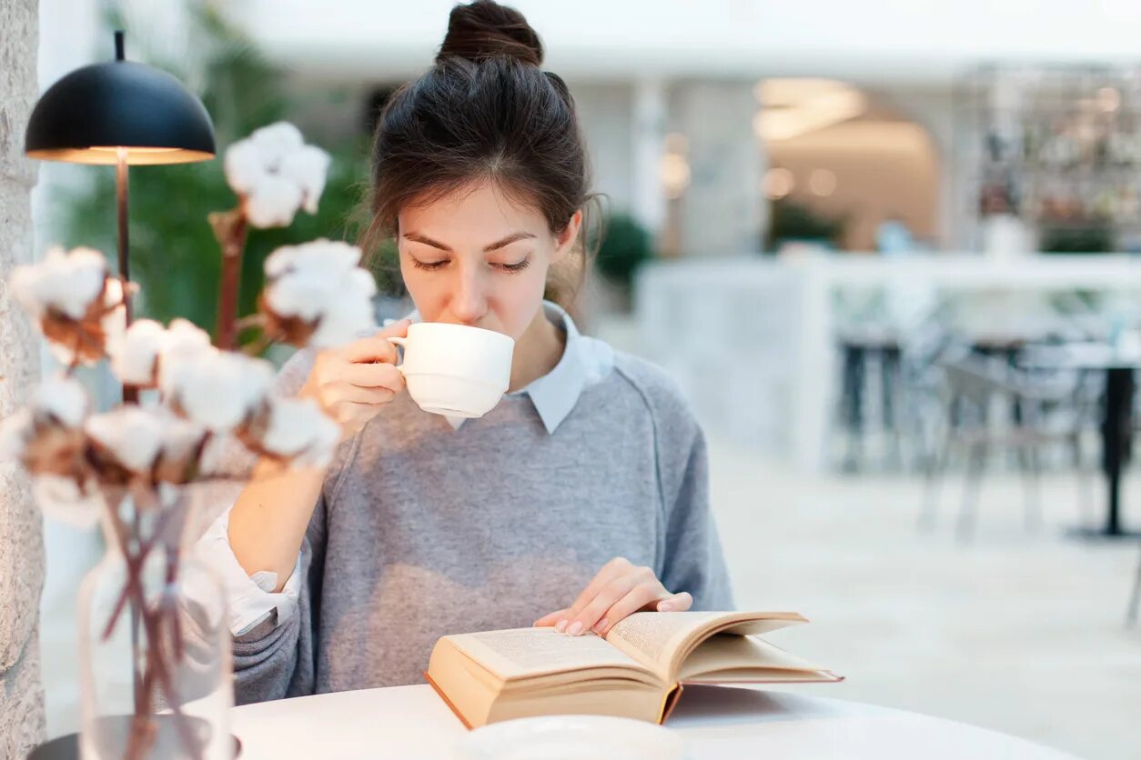 Читаю книги пью кофе. Девушка пьет кофе и читает книгу в кафе. Чтение в кофейне. Девушка читает книгу и пьет кофе. Девушка читает книгу в кафе.