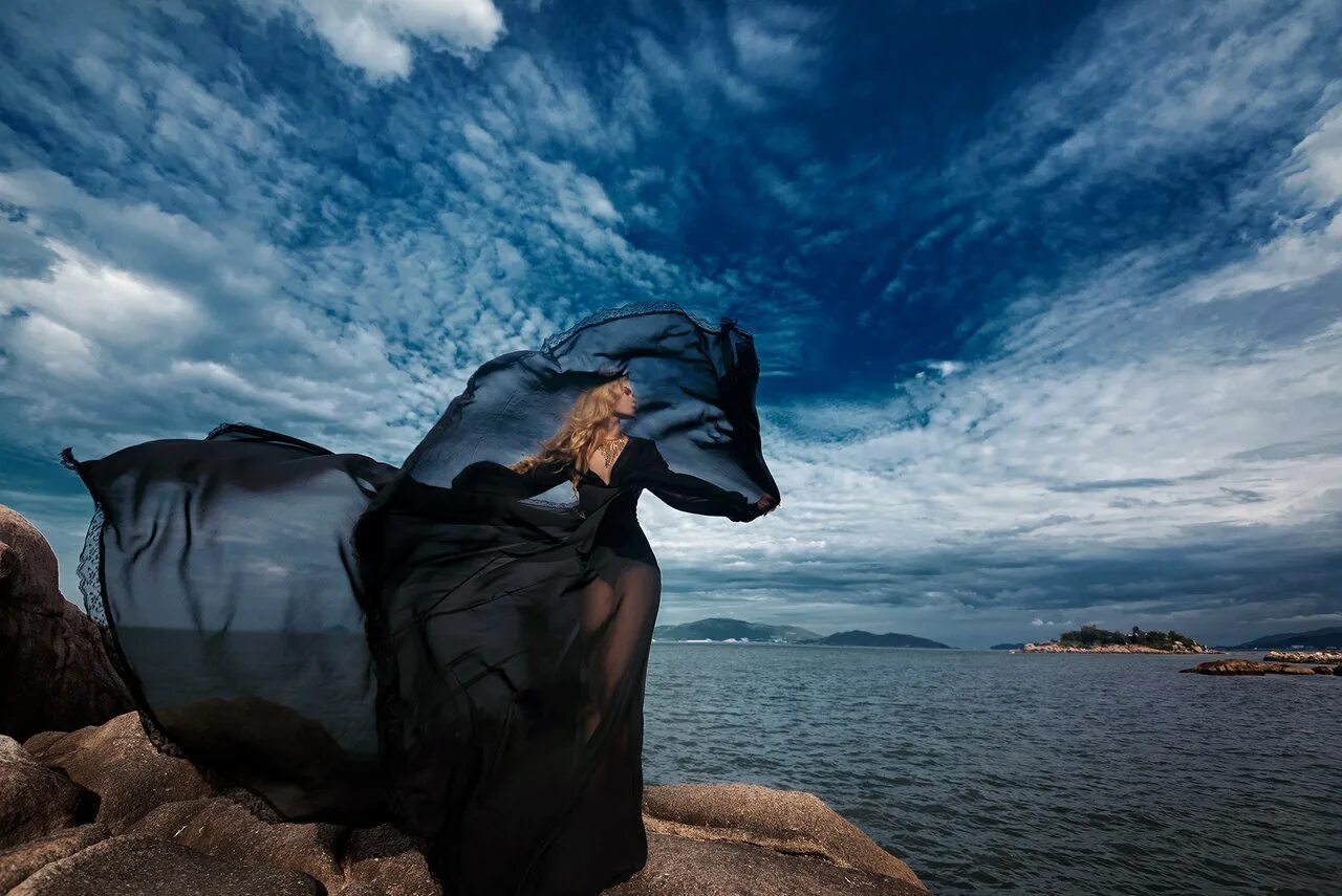 Девушка в платье на ветру. Черное платье на ветру. Девушка в развевающемся платье на море. Ткань развивается на ветру.