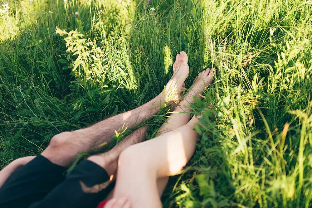 Обнимает ноги девушки. Ноги на природе. Ноги на траве. Пара лежит на траве. Девочки ноги на природе.