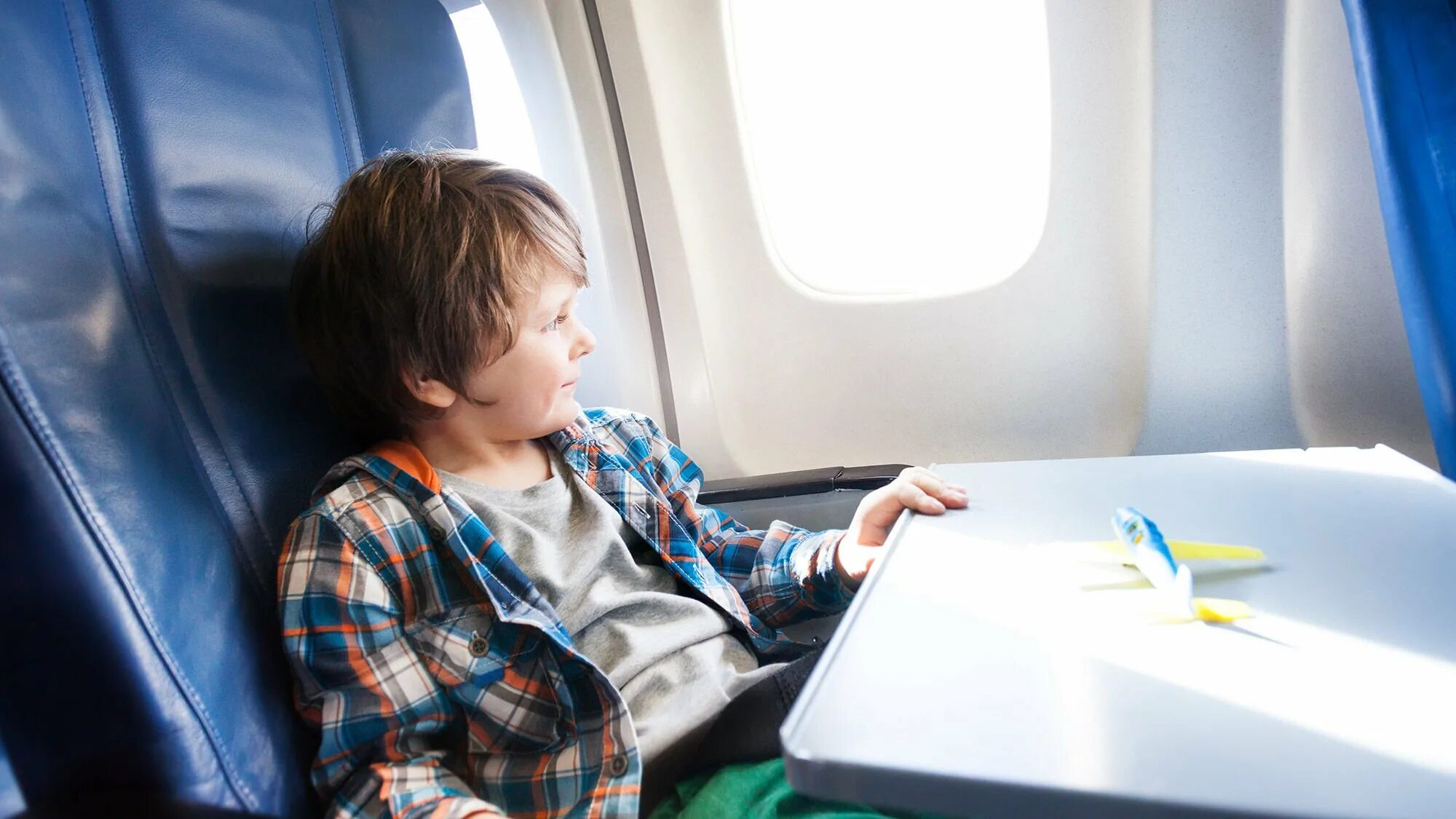 Подросток в самолете без сопровождения. Ребенок в самолете без сопровождения. Ребенок с самолетом в руках. Важно при путешествии с детьми на самолете.
