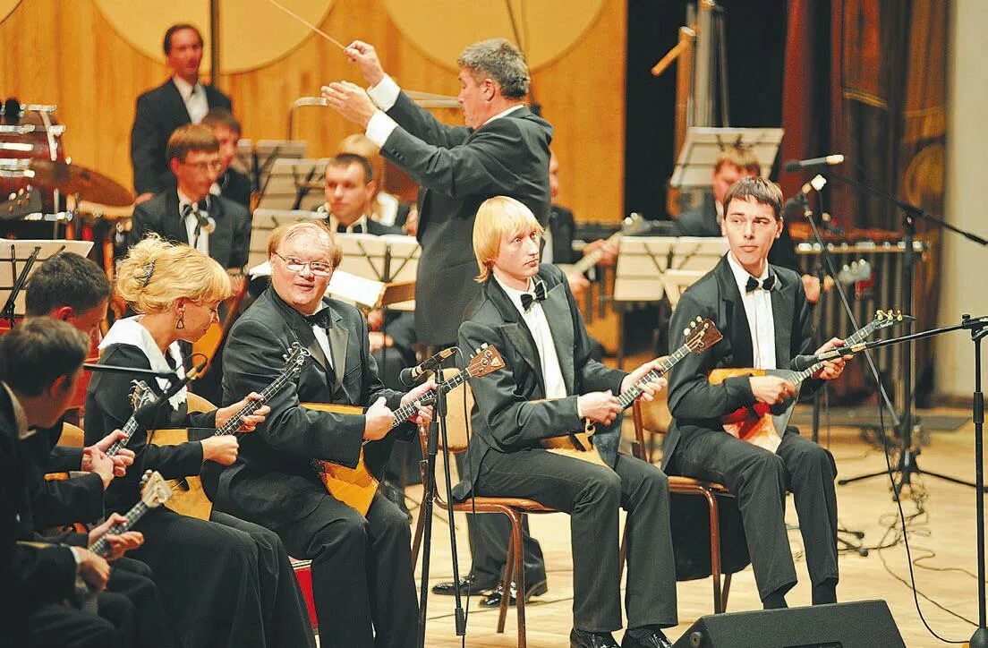 Кем является оркестр. Дирижер Самарской филармонии в 1986 году. Балалайка в оркестре. Оркестр из балалаек. Балалайки Оркестровые.