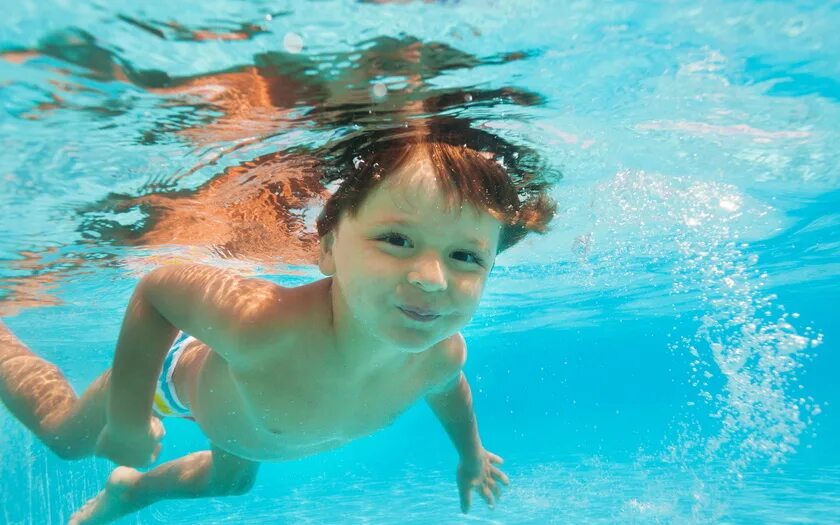 Мальчик плавает под водой. Мальчик плавает в бассейне. Мальчик плавает в одежде. Ребенок под водой. Закрыли в бассейне в воде