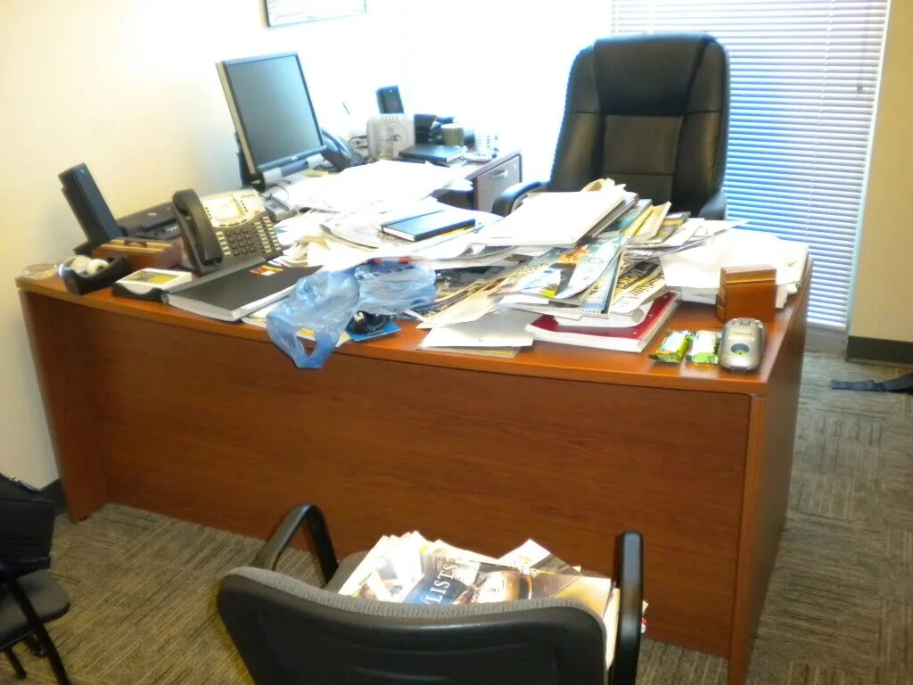Вынесено в кабинете. Письменный стол заваленный бумагами. Письменный стол заваленный бумагами в офисе. Бумаги на столе. Бумаги на столе в офисе.