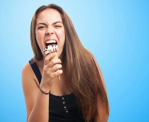 Девушки поют на языке. Девушка ест эскимо. Человек кусает мороженое. Девушка грызет.