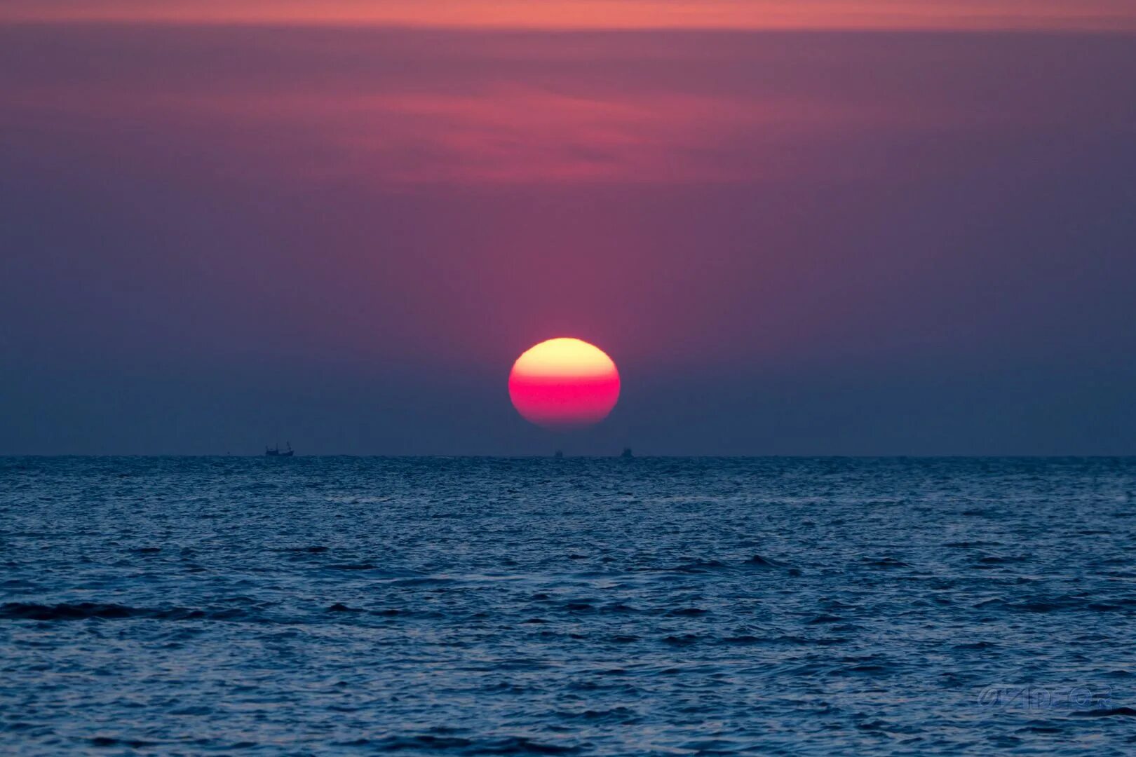 Солнце уходит за горизонт. Закат солнца на море. Розовое солнце. Закат солнца над морем. Розовый закат над морем.