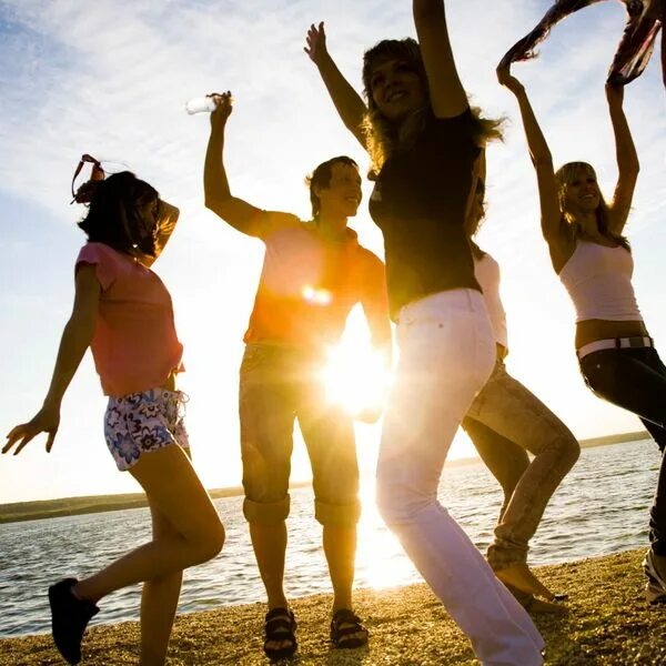 Люди веселятся на природе. Девушка танцует на пляже. Танец лета. Молодежная тусовка.