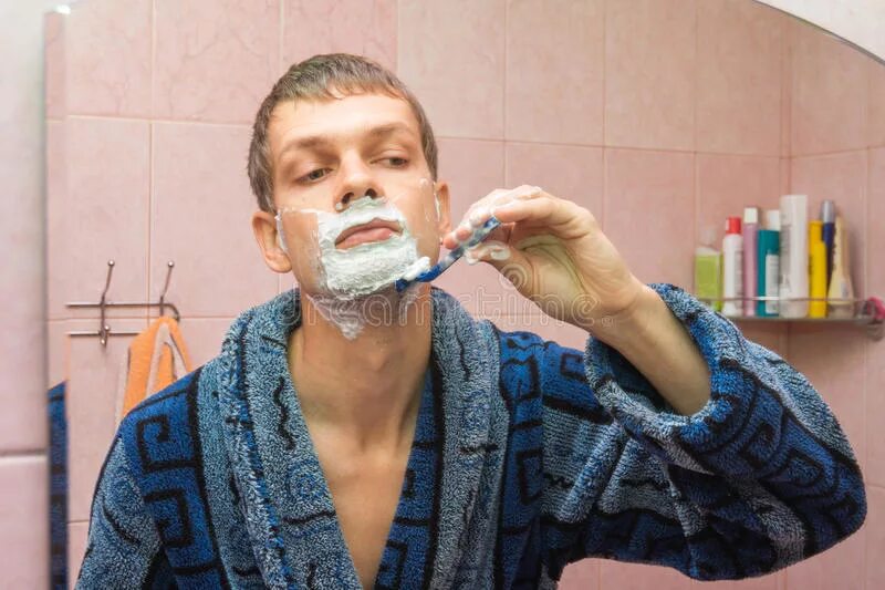 Мужчина бреется. Мужчина бреется в ванной. Мужчина бреется перед зеркалом. Молодой парень бреется. Мужчины бреет видео