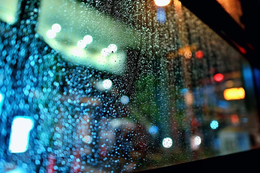 Капли на стекле. Дождливый город через окно. Блики на окне. Капли дождя на стекле. Видеть сквозь стекло