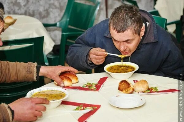 Еда для бездомных. Столовая для бомжей. Мужчина в столовой. Мужчина обедает в столовой. Люди едят в столовой.