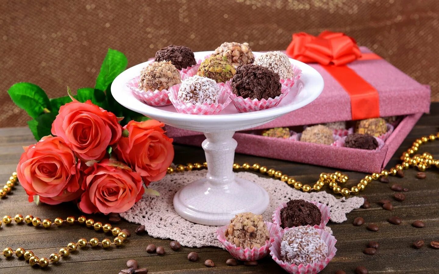 На праздник купили пирожные и конфеты. Цветы с конфетами. Шоколадные конфеты и цветы. Красивые сладости. Конфеты на столе.