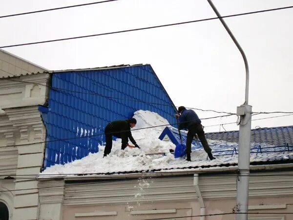 Мужик снег кидает с крыши.