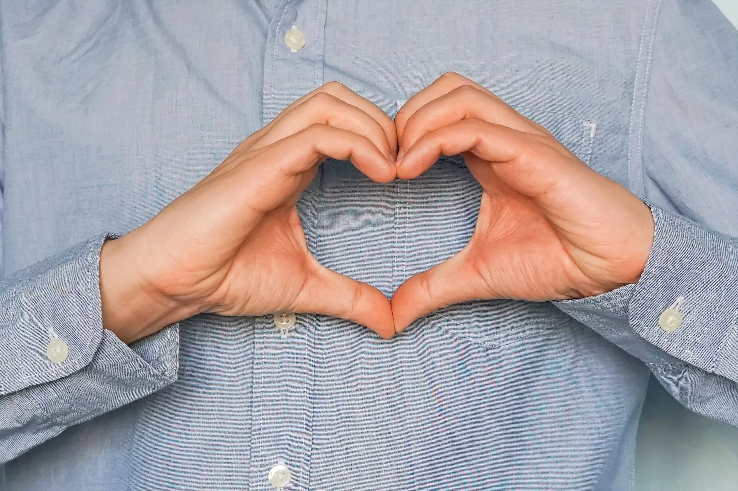 мужчина показывает сердечко руками. человек делает сердечко. человек показывает серде. сердце в руках. человек делает сердечко.