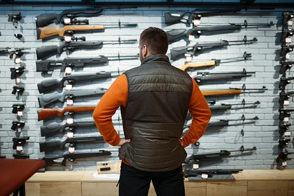 Оружейный магазин. Витрина для оружия. Магазин с винтовками магазин. Человек с оружием.