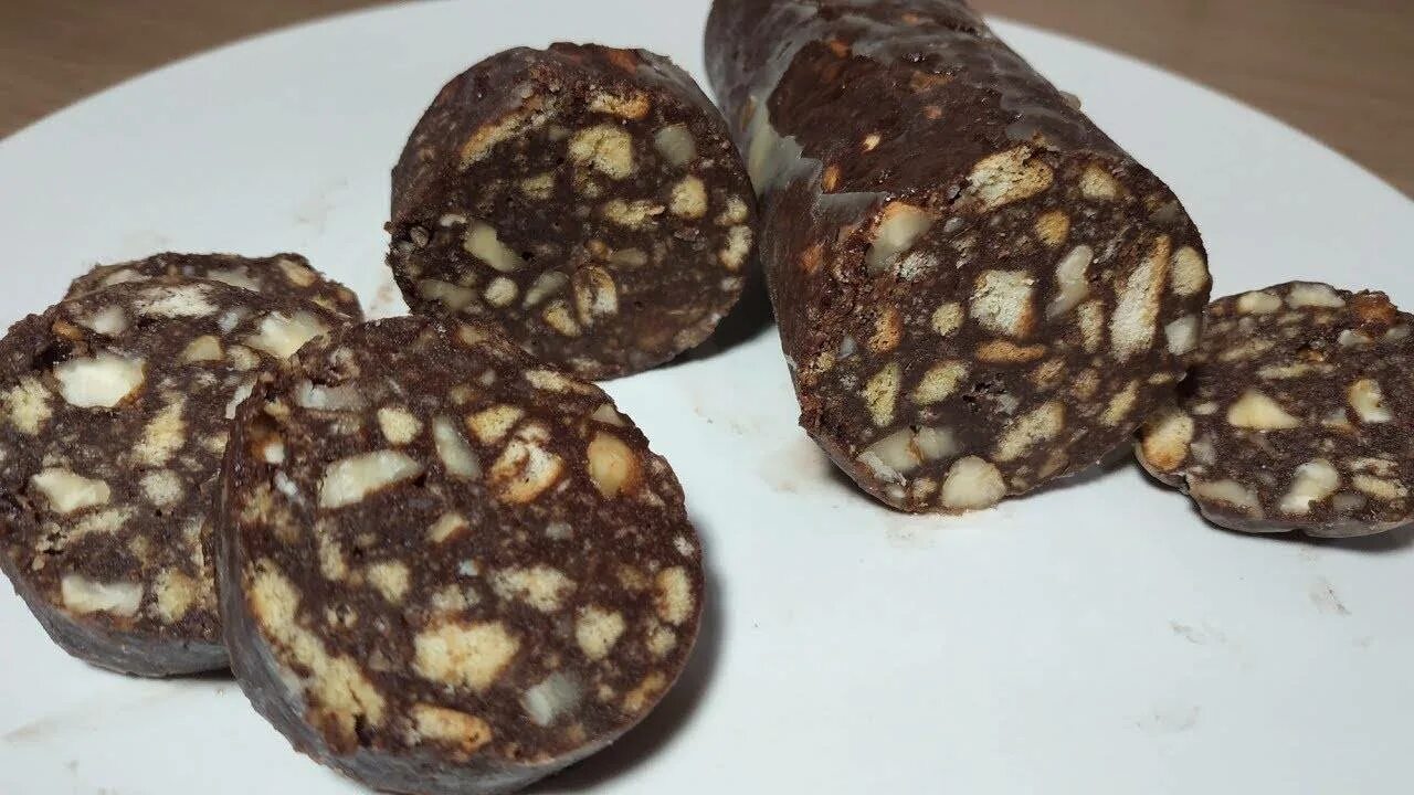 Колбаска из печенья со сгущенкой и орехами. Шоколадная колбаса. сладкая колбаска из печенья и какао. шоколадная колбаса из печенья. шоколадная колбаса со сгущенкой и печеньем.