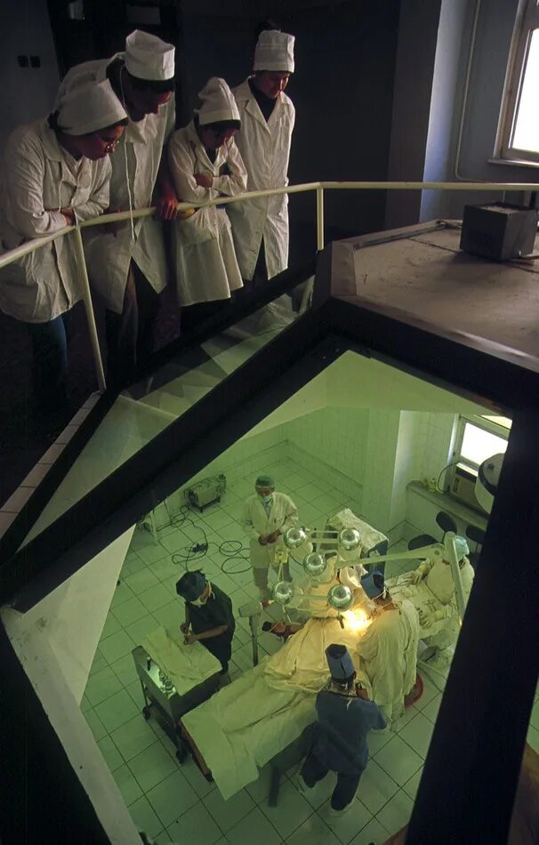 Студенты наблюдают за операцией. В операционной студенты наблюдают за стеклом. Операция студенты наблюдают сверху.