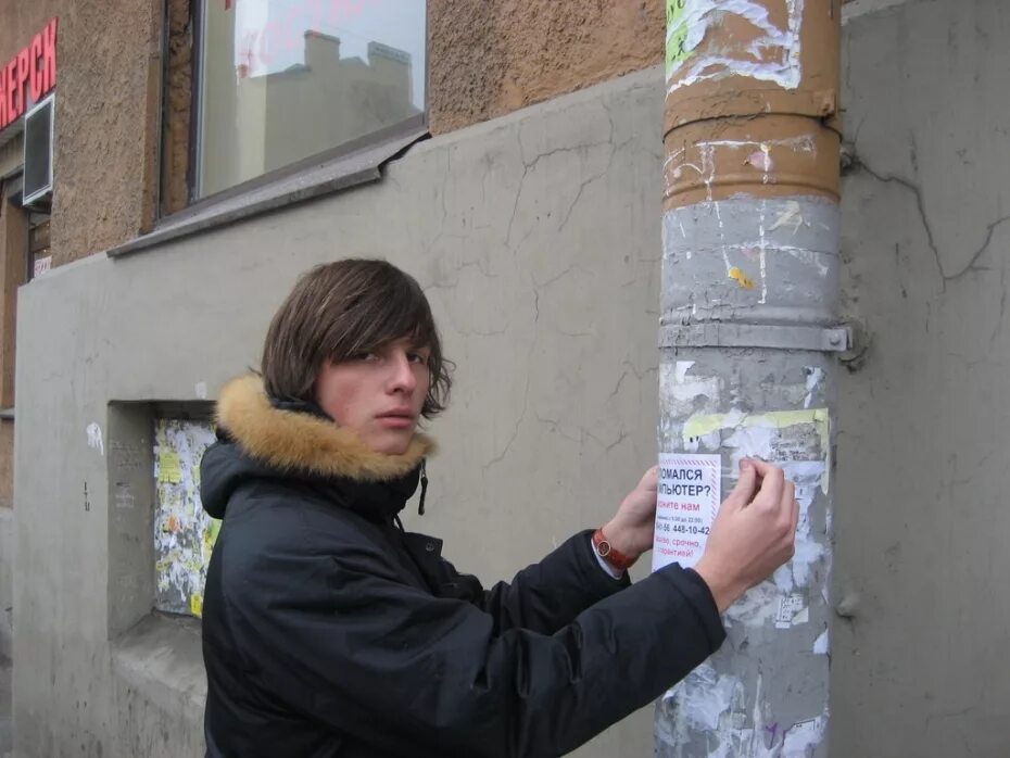 Доска объявлений на улице. Девушка расклеивает объявление. Расклейка листовок. Можно расклеивать листовки. Расклейка плакатов.