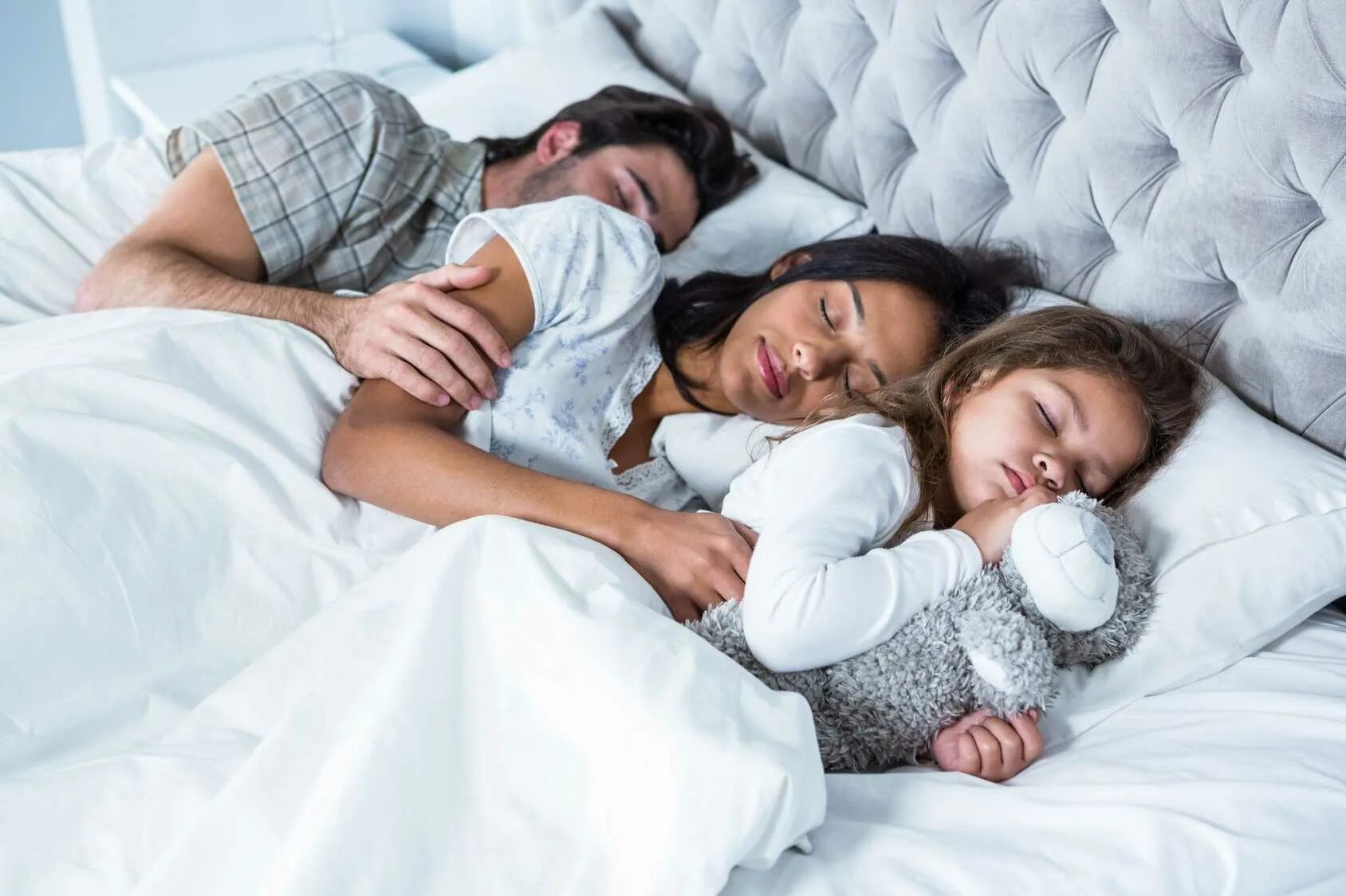 Семья на кровати. Счастливая семья в постели.