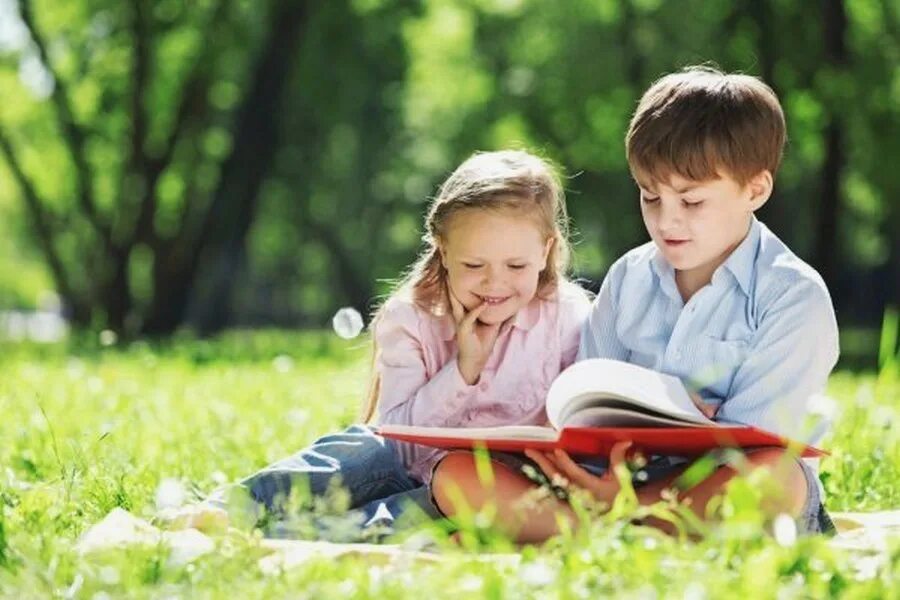Развлечение братья и сестры. Kids reading in Summer. The children lay reading in the Park.