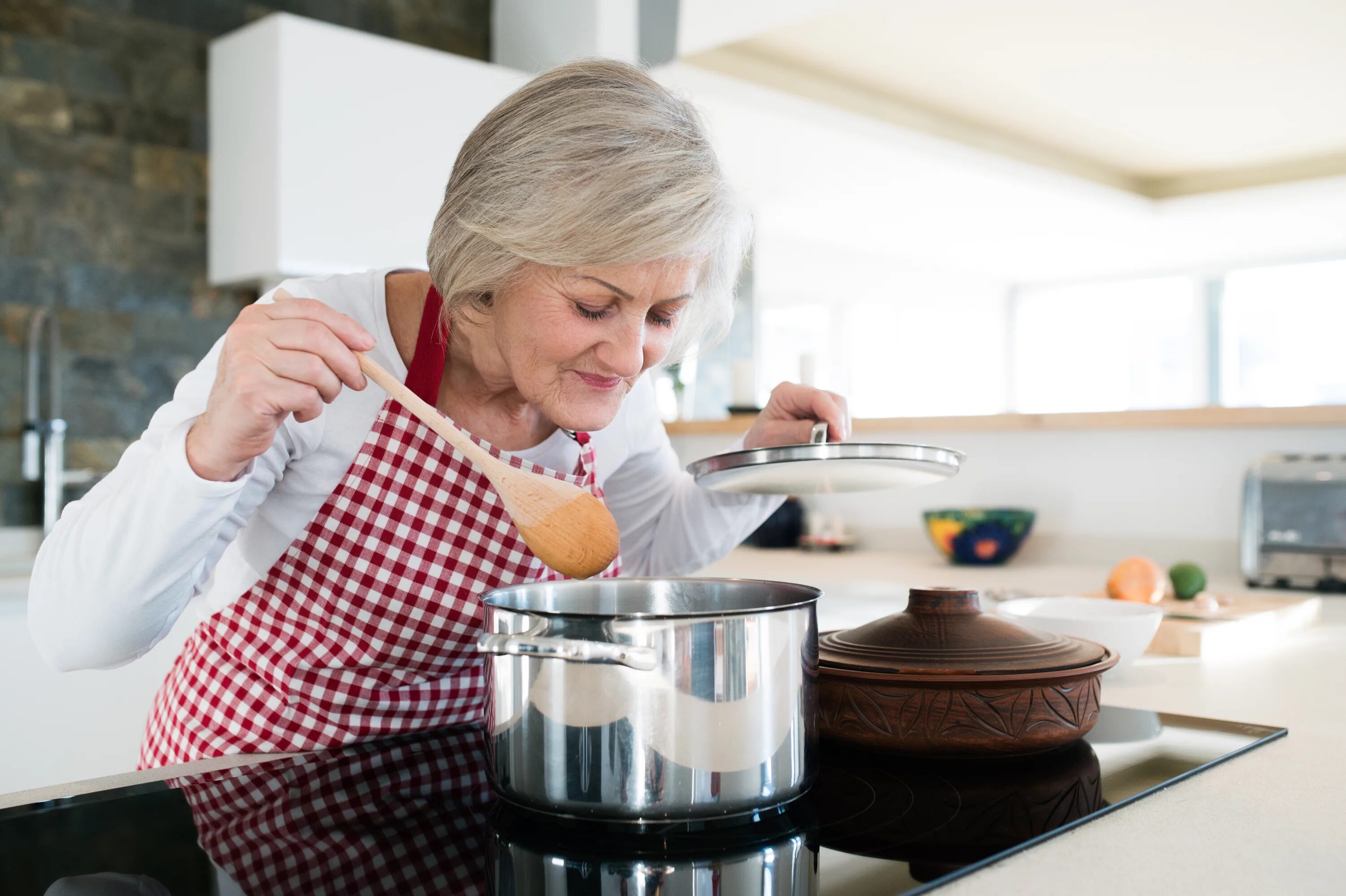 Бабушка варит. Бабушка готовит. Бабуля на кухне. Бабушка готовит еду. Женщина с кастрюлей.