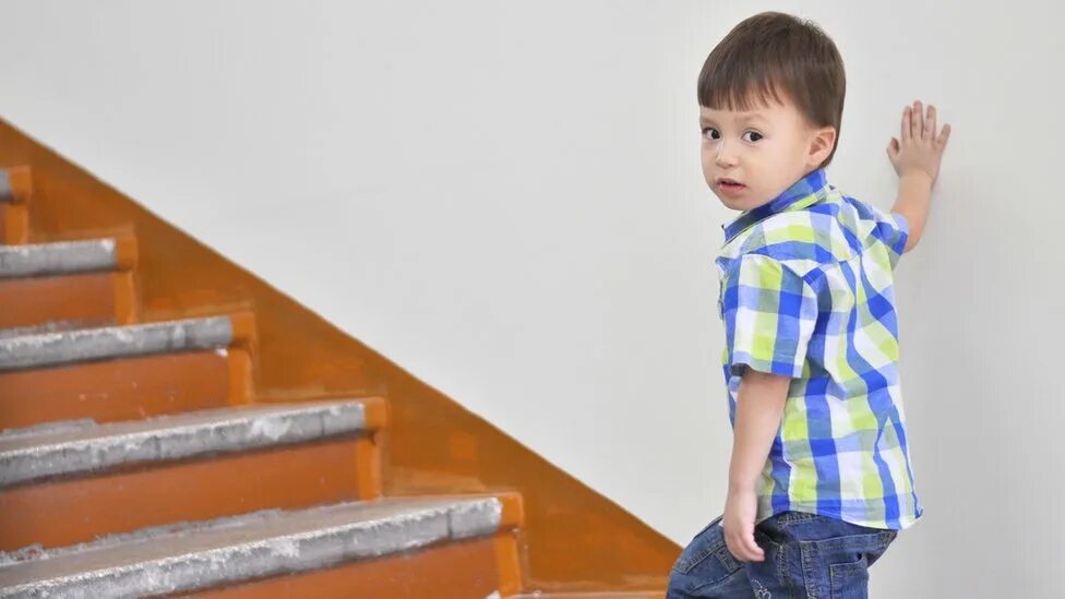 Мальчик поднимается по лестнице. Ребенок ползет по ступенькам. Ребенок идет по ступенькам. Мальчик идет по лестнице. Фотосессия на лестнице для детей школьников.