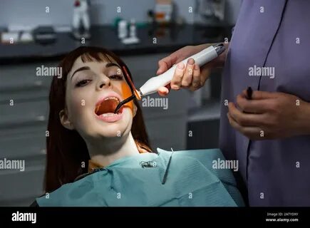 Dentist assistant using dental treatment with dental curing UV lamp on the ...