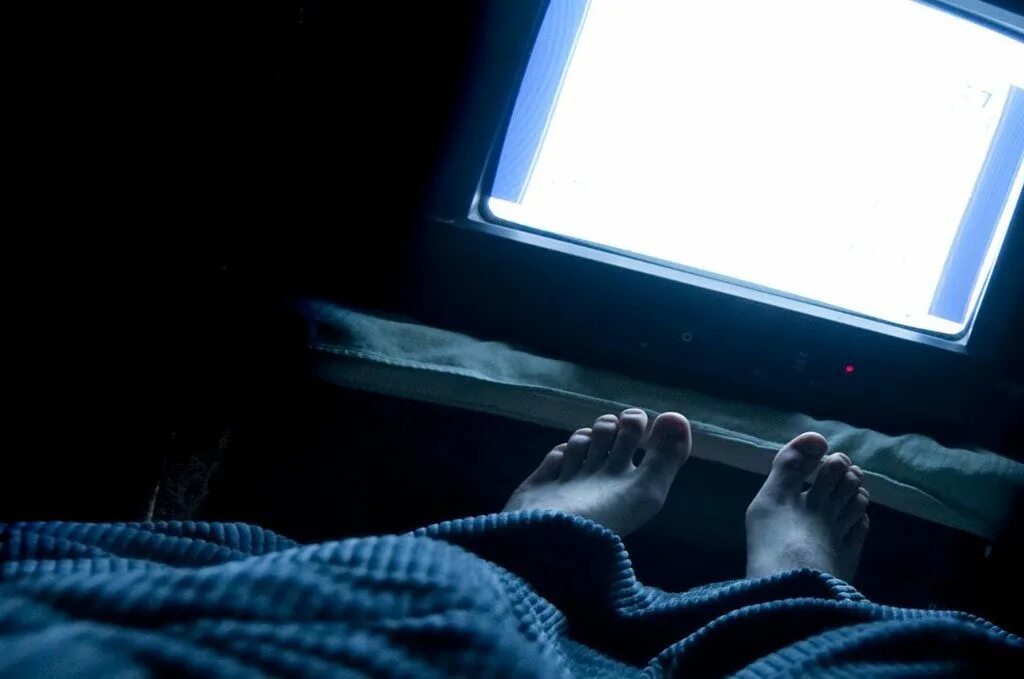 Телевизор перед сном. Ноги на кровати в темноте. Мужские ноги на кровати в темноте. Ночью перед телевизором. Ноги перед телевизором.