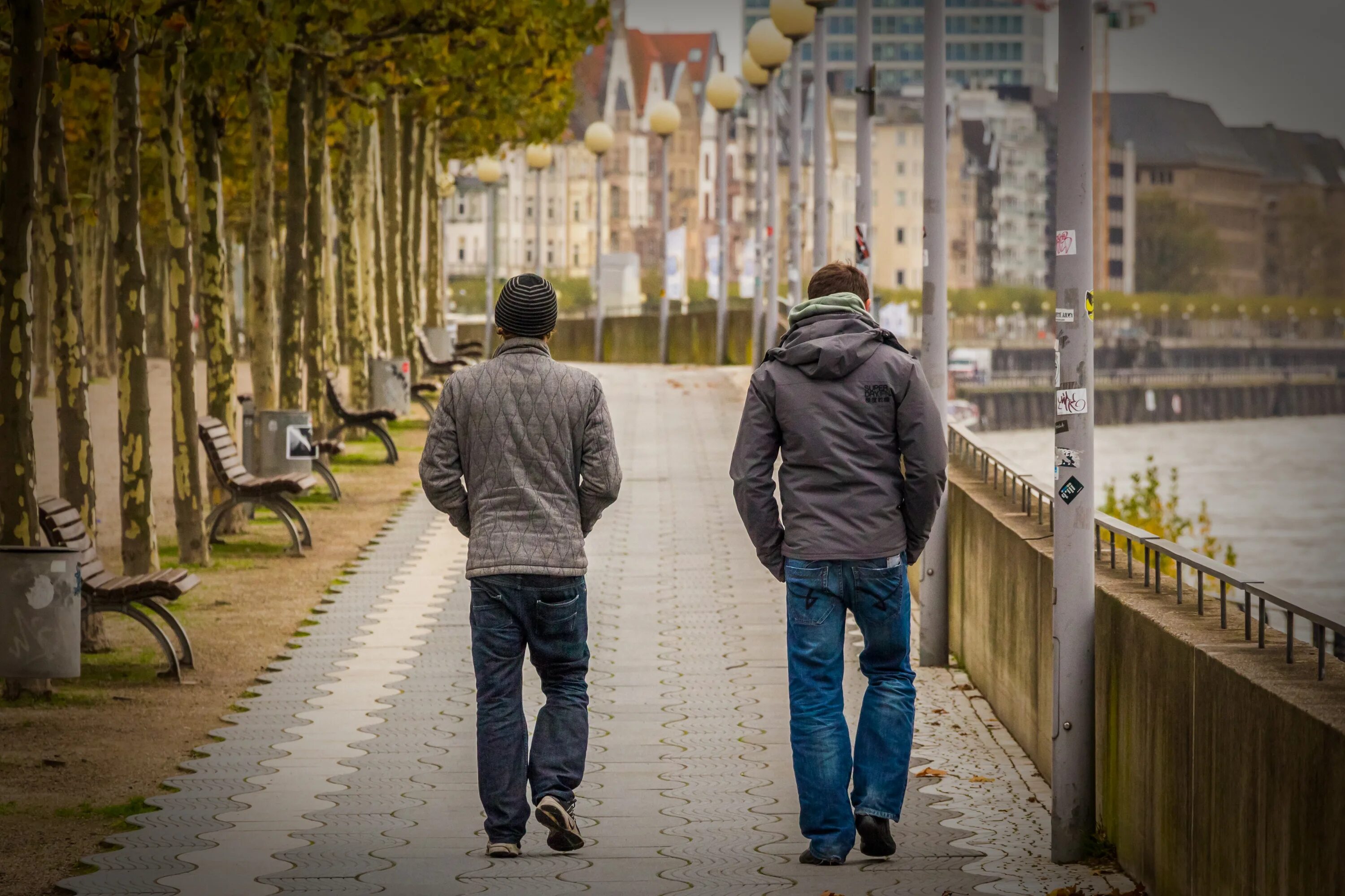 Гулять по улице. Друзья на прогулке. Два парня со спины. Прогулка по городу фото.