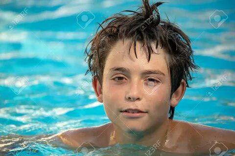 12 year old boy playing in the swimming pool of his house during the summer...