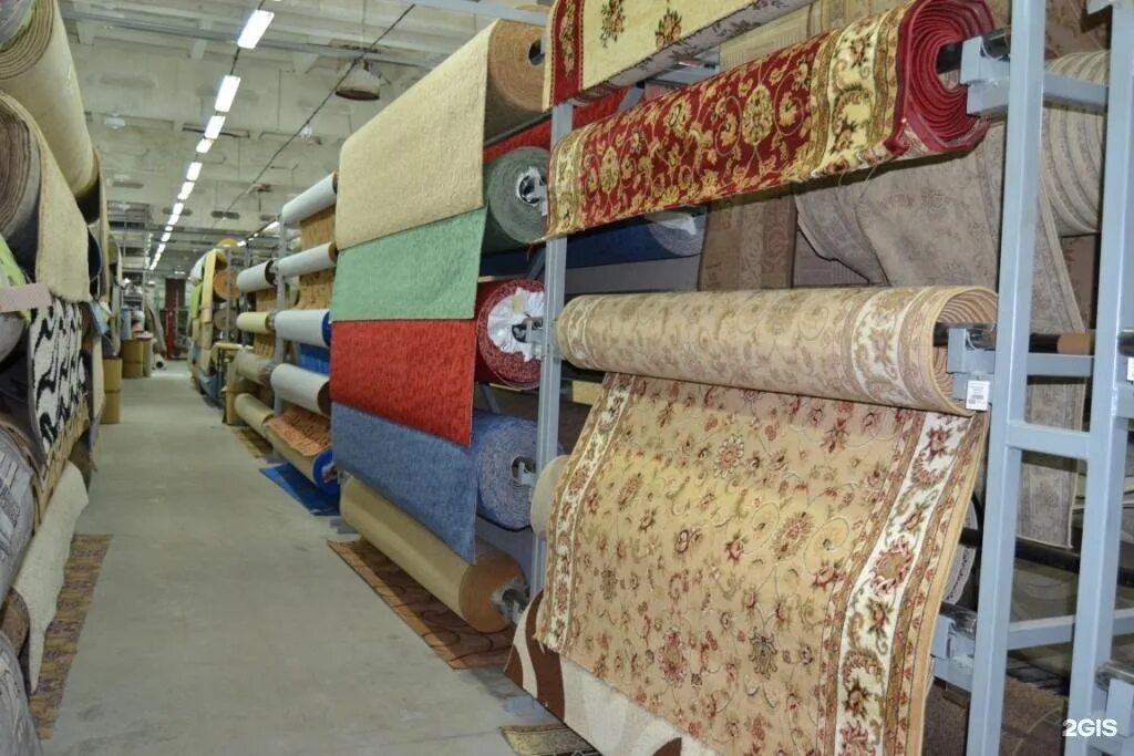 Где купить коврове. Ассортимент ковров. Стеллаж для ковровых дорожек. Магазин паласов и ковров. Выкладка ковров.