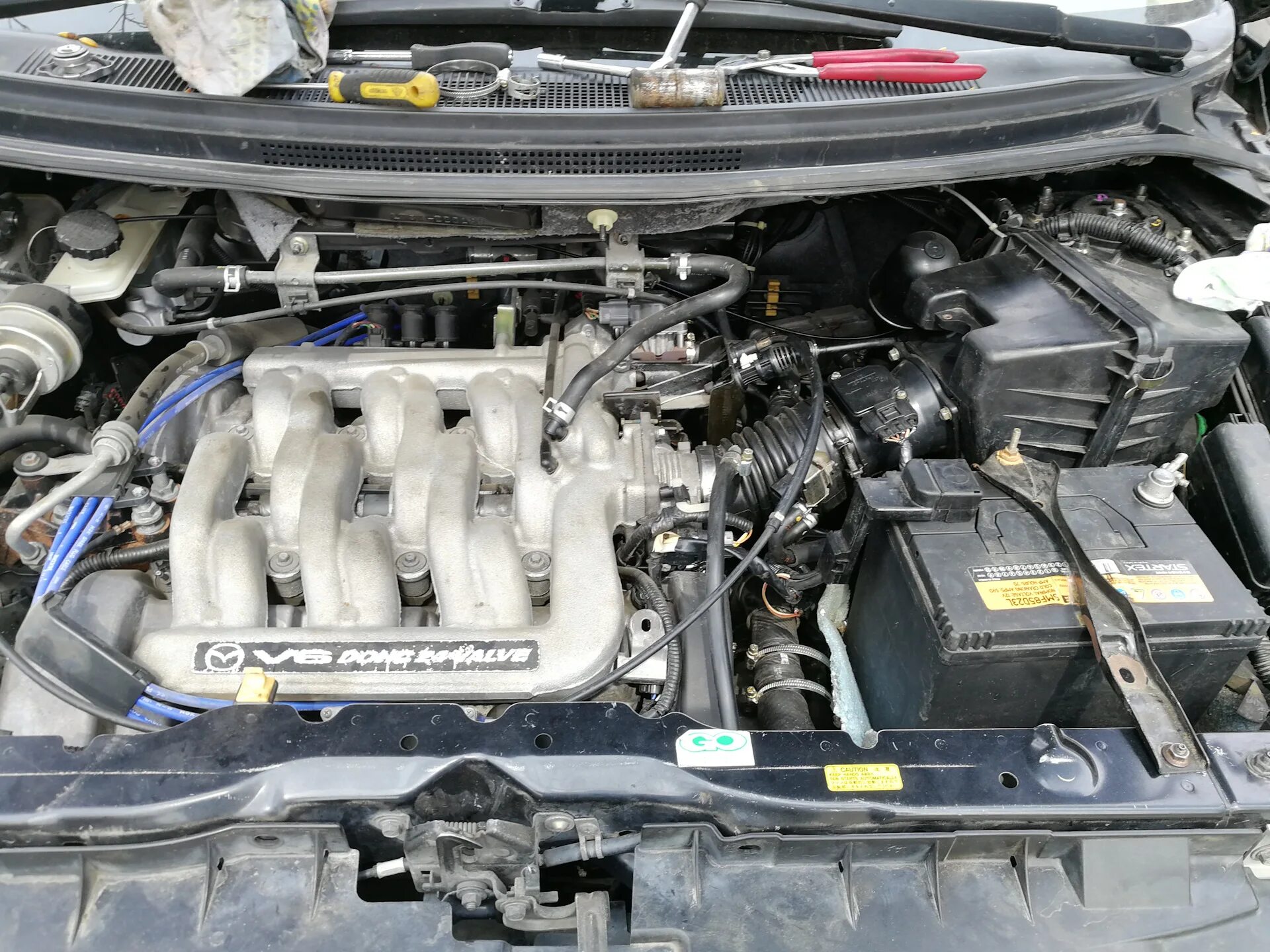 Мазда мпв зажигания. Mazda MPV 3.0 под капотом. Мазда МПВ 2.5 бензин. АКБ Мазда МПВ 2.5. Mazda MPV под капотом.