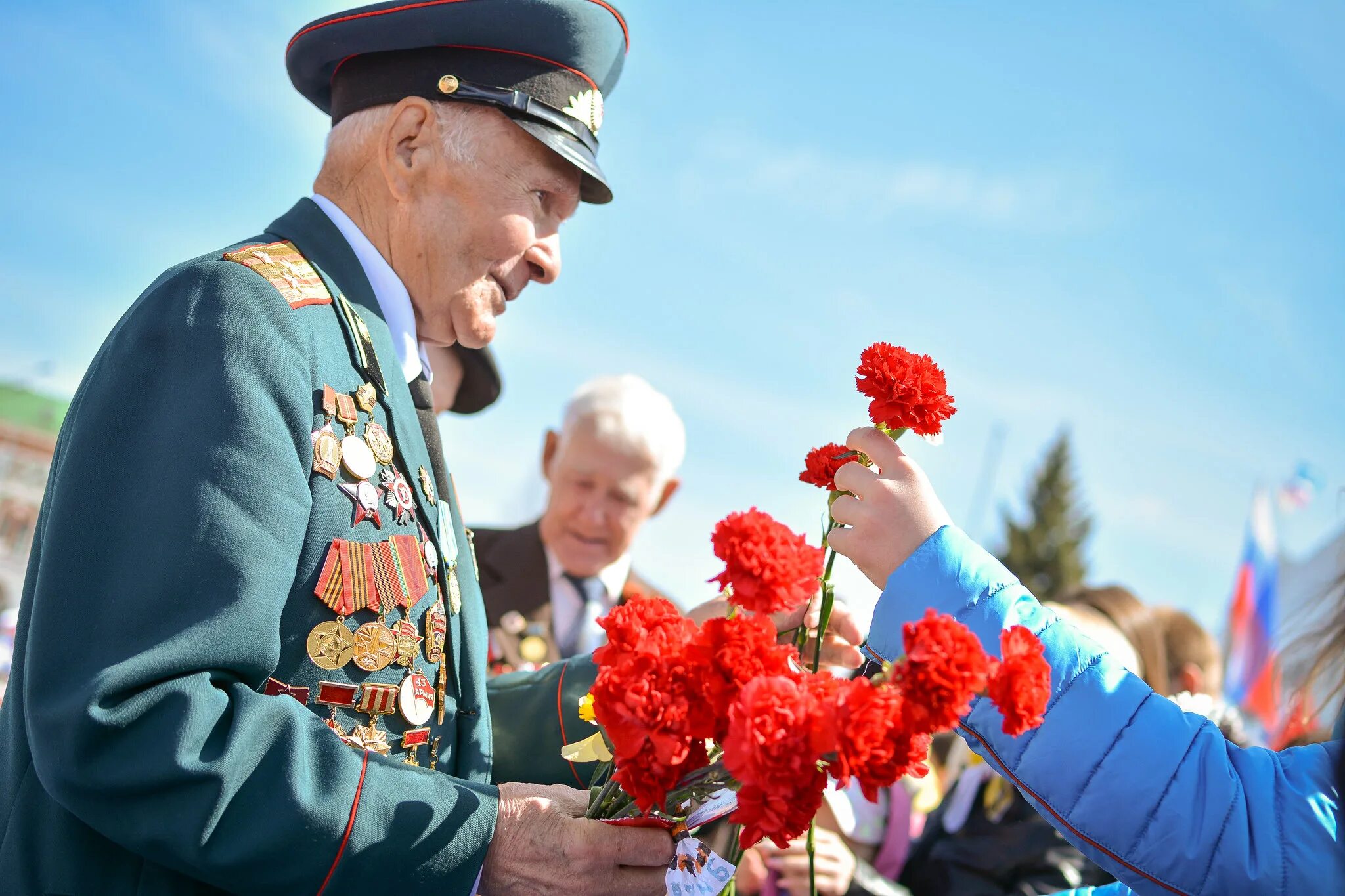 Суть времени 9 мая. День Победы ветераны. С днем Победы. Ветеран с гвоздиками. Цветы ветеранам.