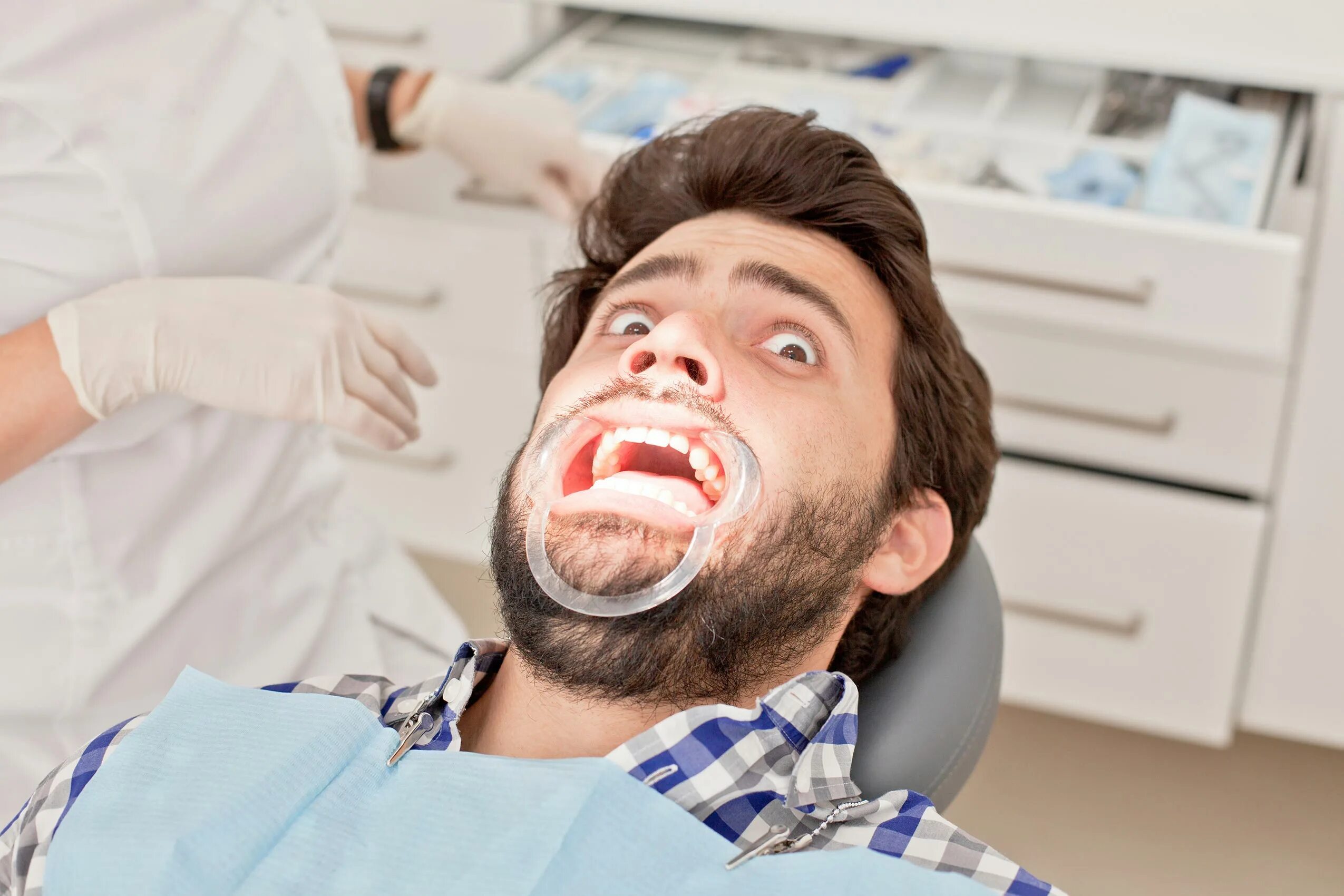 Есть ли зубной врач. Пациент улыбается. Пациент в стоматологическом кресле. Пациент у дантиста.