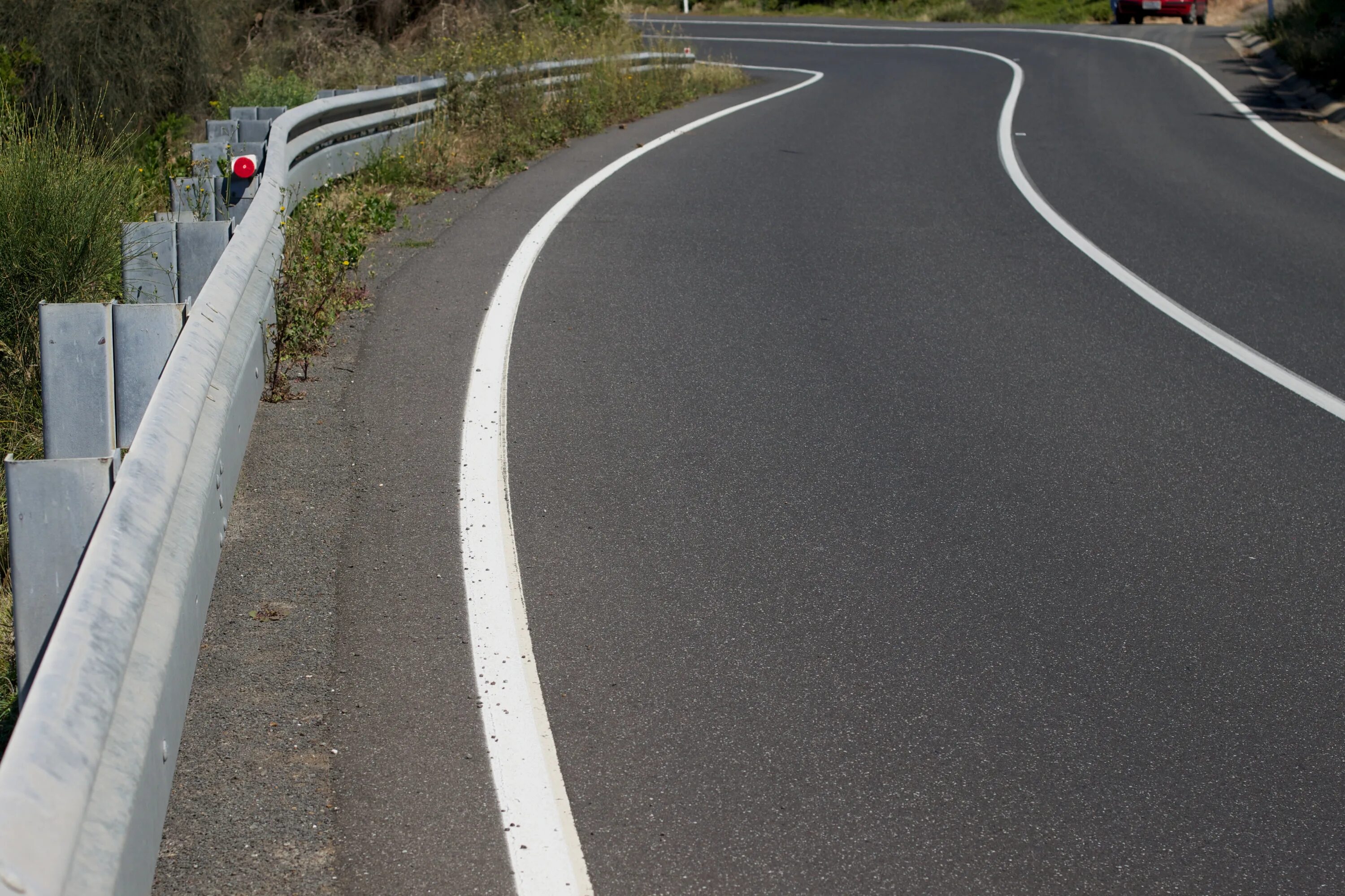 Шоссе покрыто асфальтом. Дорога с желтой полосой. Разделительная полоса на дороге. Однополосная дорога. Велодорога асфальтобетон.