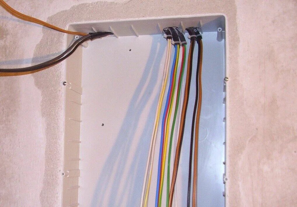 Расключение электрического щитка. Вводной кабель в квартиру. Провода на стене. Укладка кабеля в щитке.