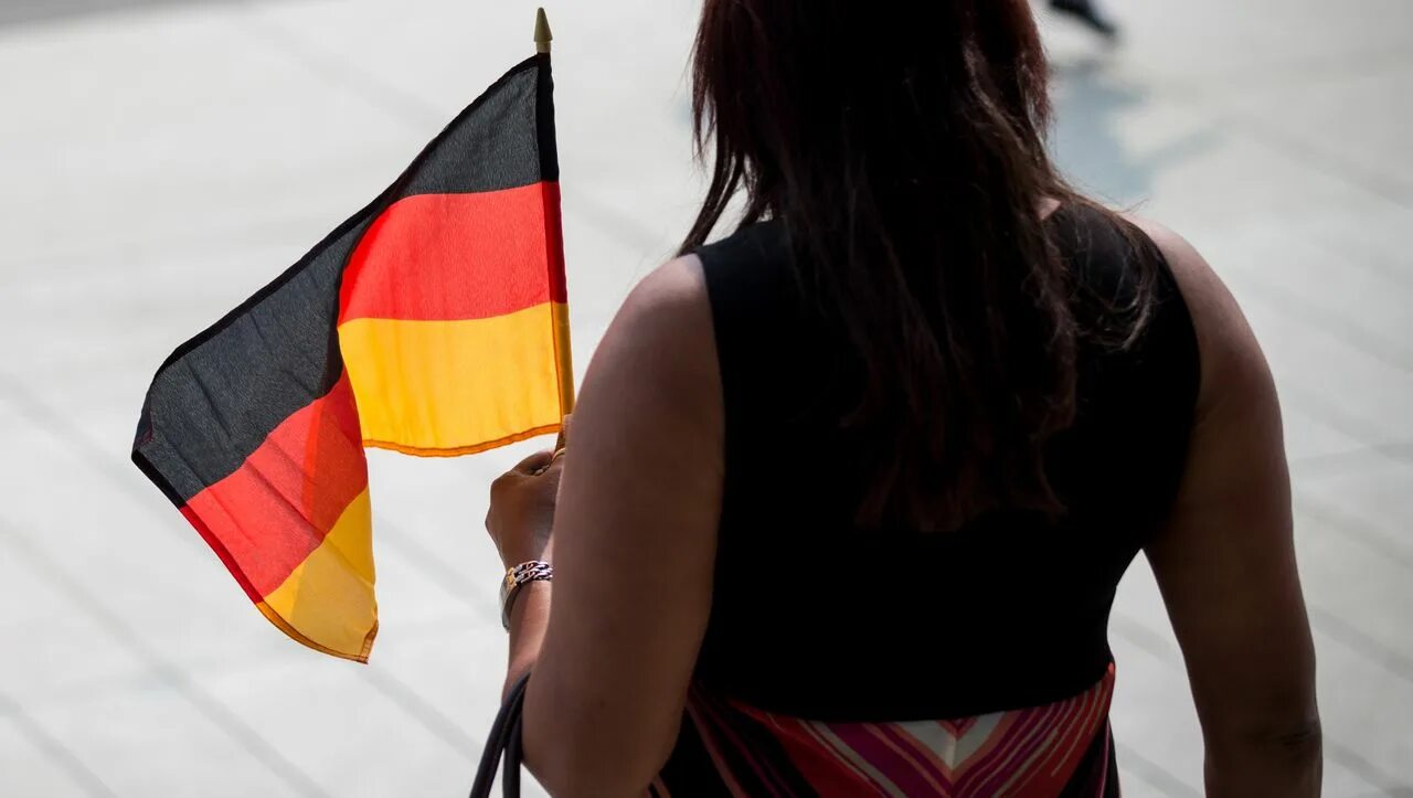 Германия для казахстанцев. Человек с флагом Германии. Девушка с флагом Германии. Иммигранты Германии образный портрет. Флаг Германии на лице.