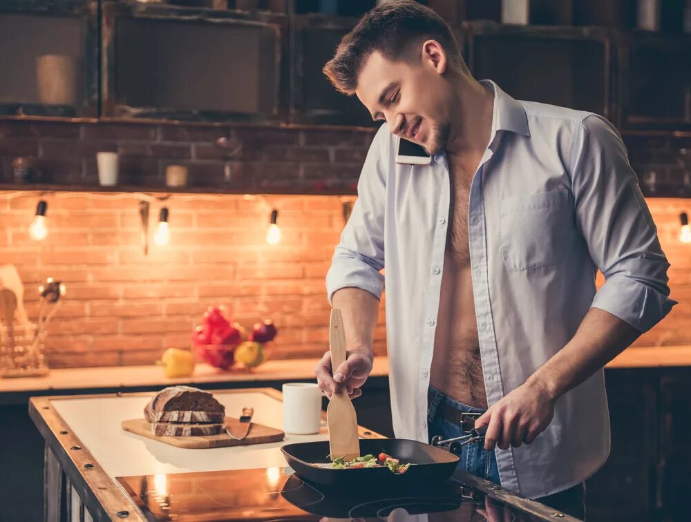 Парень стоит на кухне. Человек в фартуке. Парень на кухне. Парень готовит. Мужчина готовит на кухне.