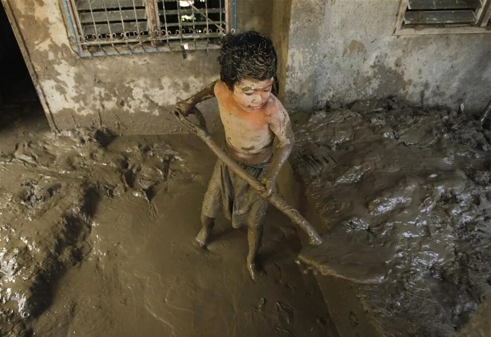 Мальчик купается в грязи.