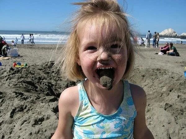 Ребенок ест песок в песочнице.