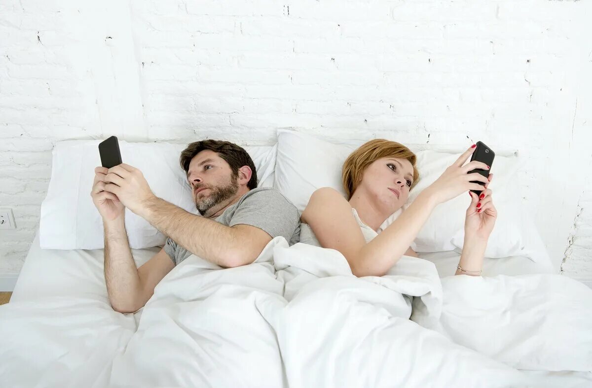 Жена лежит в постели. Мужчина в постели с телефоном. Смартфон в постели. Парень с телефоном в кровати. Женщина и мужчина в кровати с телефоном.