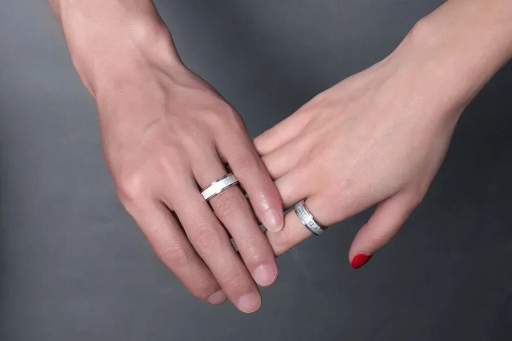 Можно ли серебряное обручальное кольцо. Стильные обручальные кольца на руках. Серебряное обручальное кольцо на пальце. Парные помолвочные и обручальные кольца. Плоские обручальные кольца на руке.