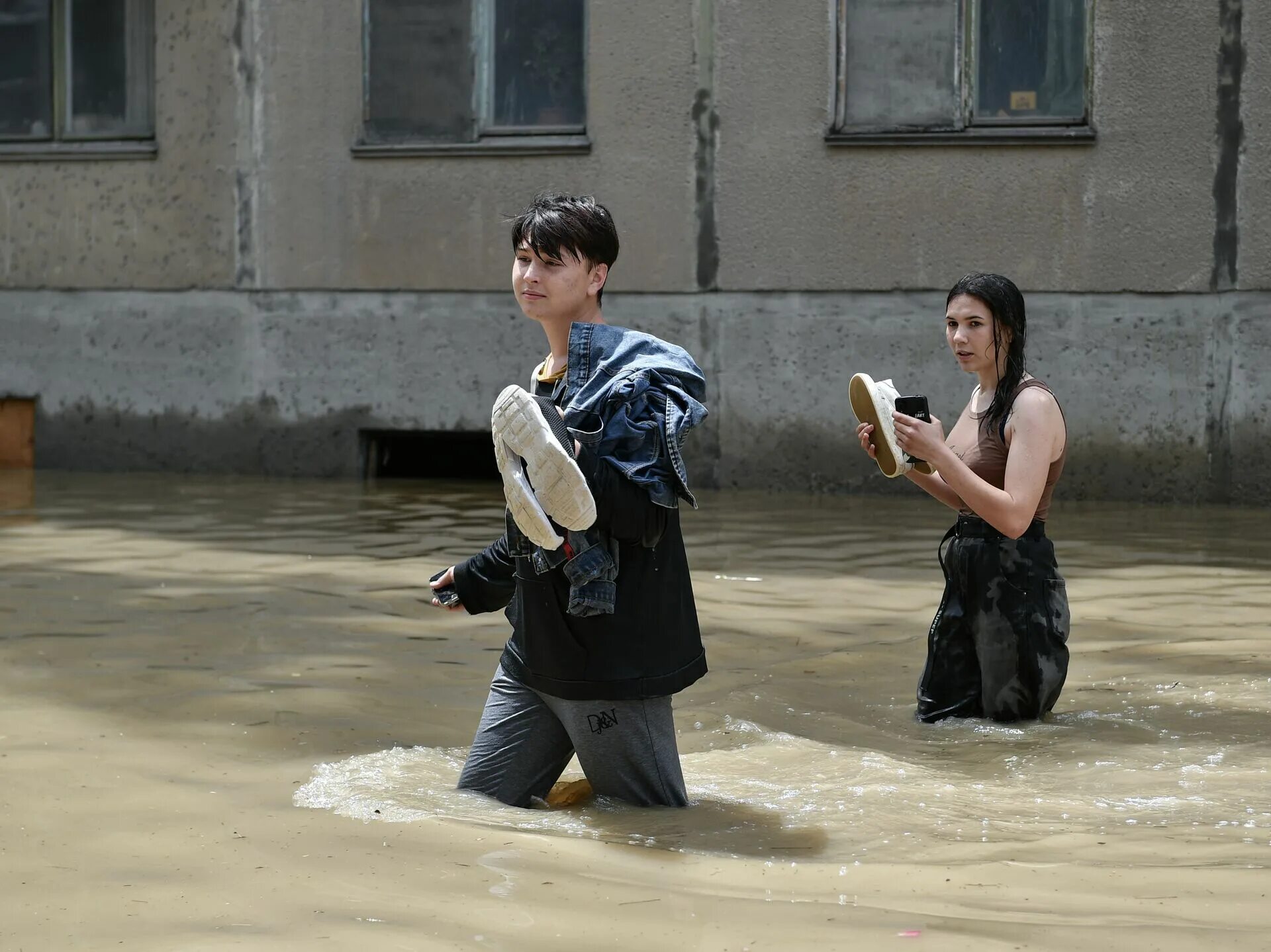 Девушки ходят по лужам после потопа. Девушки в сапогах в наводнении в венеции. Наводнение смешно. Потоп босиком. Машину затопило.