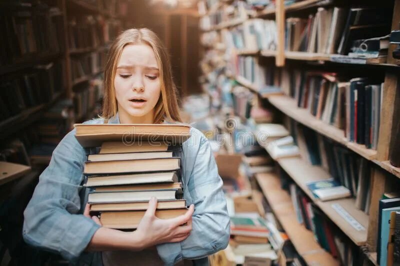 She a lot of books. Девушка в библиотеке. Девочка несет много книг. Девушка с книгой в библиотеке. Девушка несет книги.