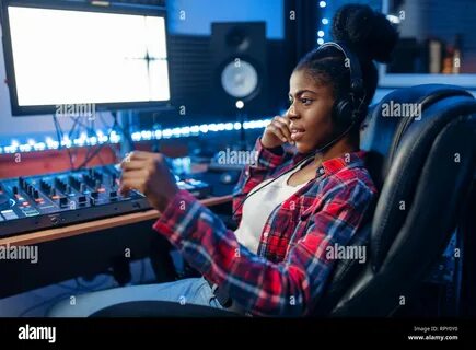 Female performer in headphones at the monitor in audio recording studio. 