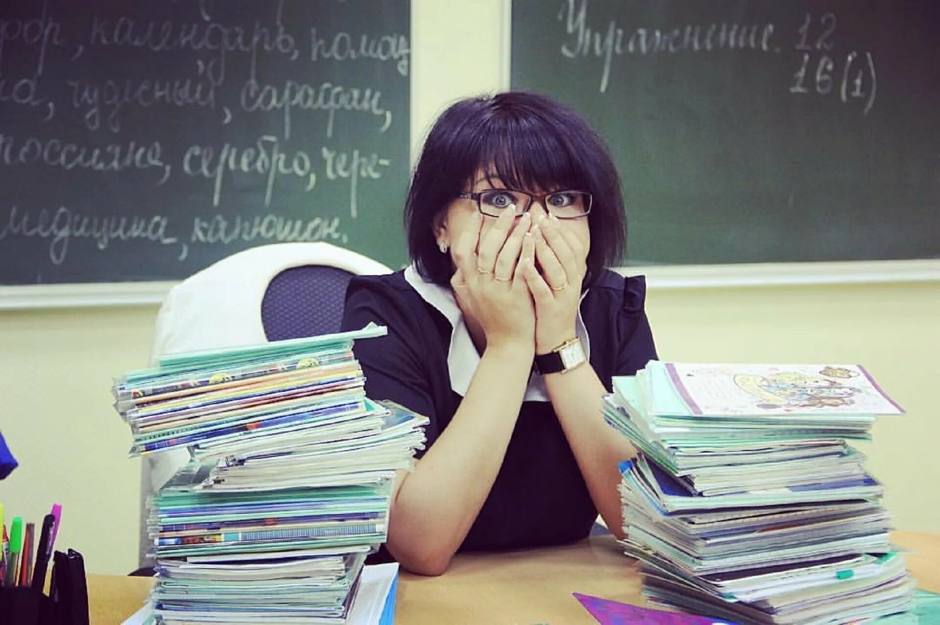 Уставший учитель. Уставший педагог. учитель проверяет тетради. учитель с тетрадями.