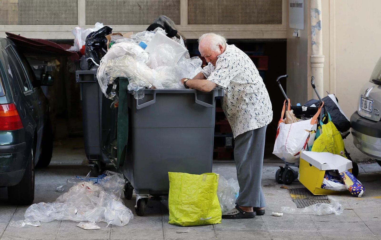 Пенсионеры роются в мусорных Баках в Германии. Роется в мусорном контейнере. Пенсионеры роются в мусорке.