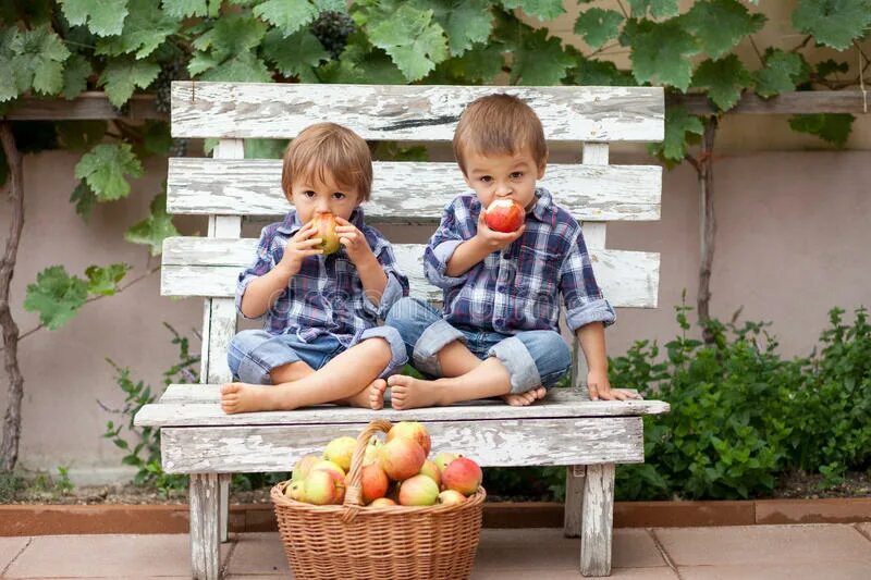В столовой уже стояли два мальчика. Мальчик на лавочке ест. Два мальчика едят. Делится яблоком. На лавочке едят яблоки.