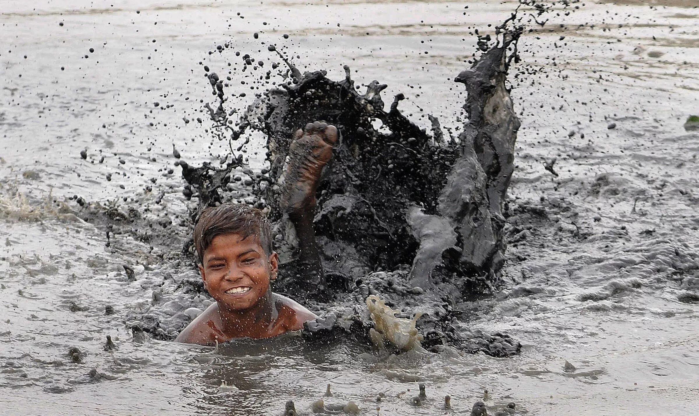 Мальчик купается в грязи. Мальчик в грязной воде.